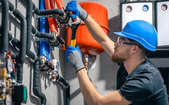Technician adjusting controls on red furnace unit in basement