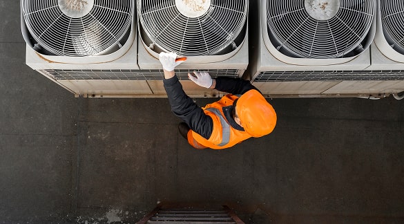 HVAC technician servicing large outdoor air conditioning unit