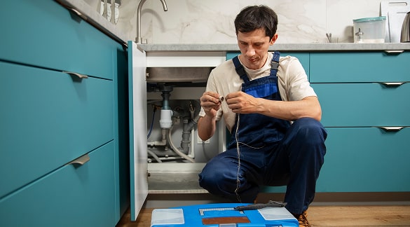 Technician repiping under a residential kitchen sink
