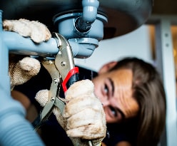 Plumber fixing leaky pipe under a sink